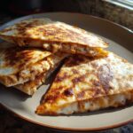 Close-up of golden-brown 3-Ingredient BBQ Chicken Quesadillas on a plate, showing melted cheese and chicken filling.