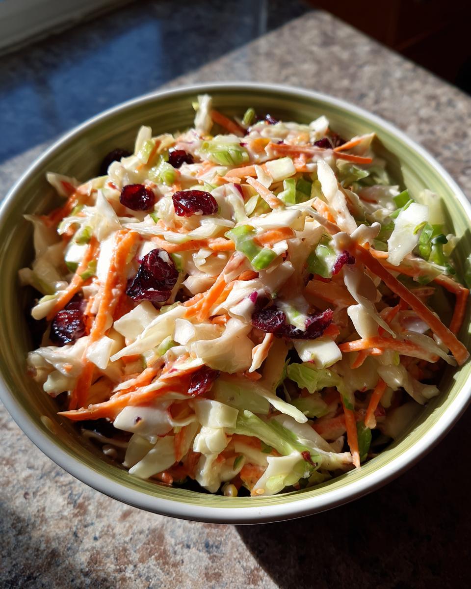 Overhead shot of a bowl filled with Apple Cranberry Coleslaw, showing ingredients like cabbage, carrots, and cranberries.