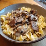 Close-up of a bowl of Classic Beef Stroganoff with egg noodles, mushrooms, and a creamy sauce.