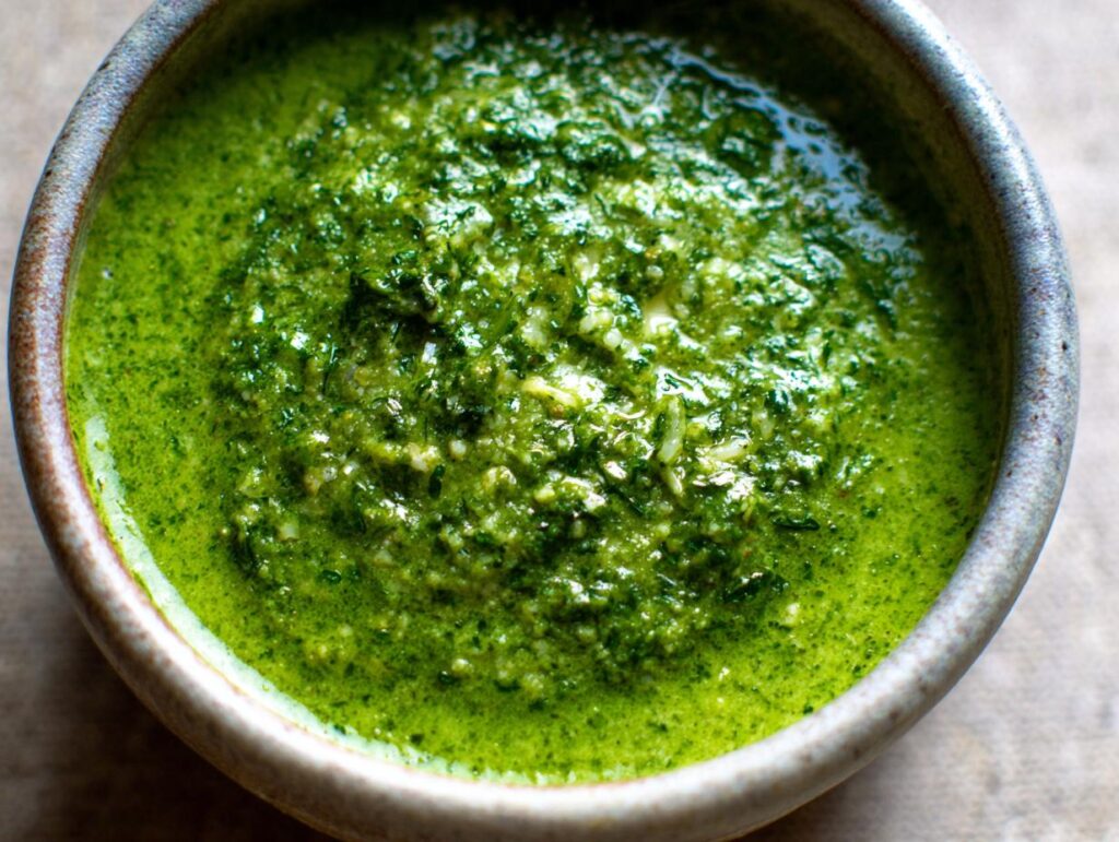 Close-up of creamy green Broccoli Cheddar Soup in a bowl, showcasing fresh ingredients.