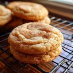 Stack of two Brown Butter Snickerdoodle Christmas Cookies sprinkled with cinnamon on a cooling rack.