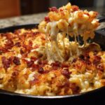 Close-up of Ultimate Cheesy Bacon Mac and Cheese with a cheese pull, showing melted cheese and crispy bacon.