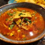 Close-up of a bowl of Chicken Tortilla Soup, garnished with tortilla chips and cilantro.