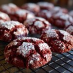 Close-up of Christmas Red Velvet Crinkle Cookies dusted with powdered sugar on a cooling rack.
