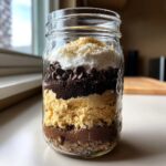 A mason jar filled with layers of ingredients for a delicious Cookie Mix in a Jar.