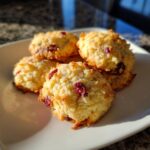 A pile of delicious Cranberry Orange Shortbread Cookies on a white plate, with visible dried cranberries.