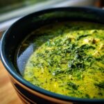 Close-up of a bowl filled with creamy spinach artichoke soup, a delicious and comforting dish.