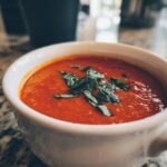 Close-up of a bowl of Creamy Tomato Basil Soup (No Cream!) garnished with fresh basil.