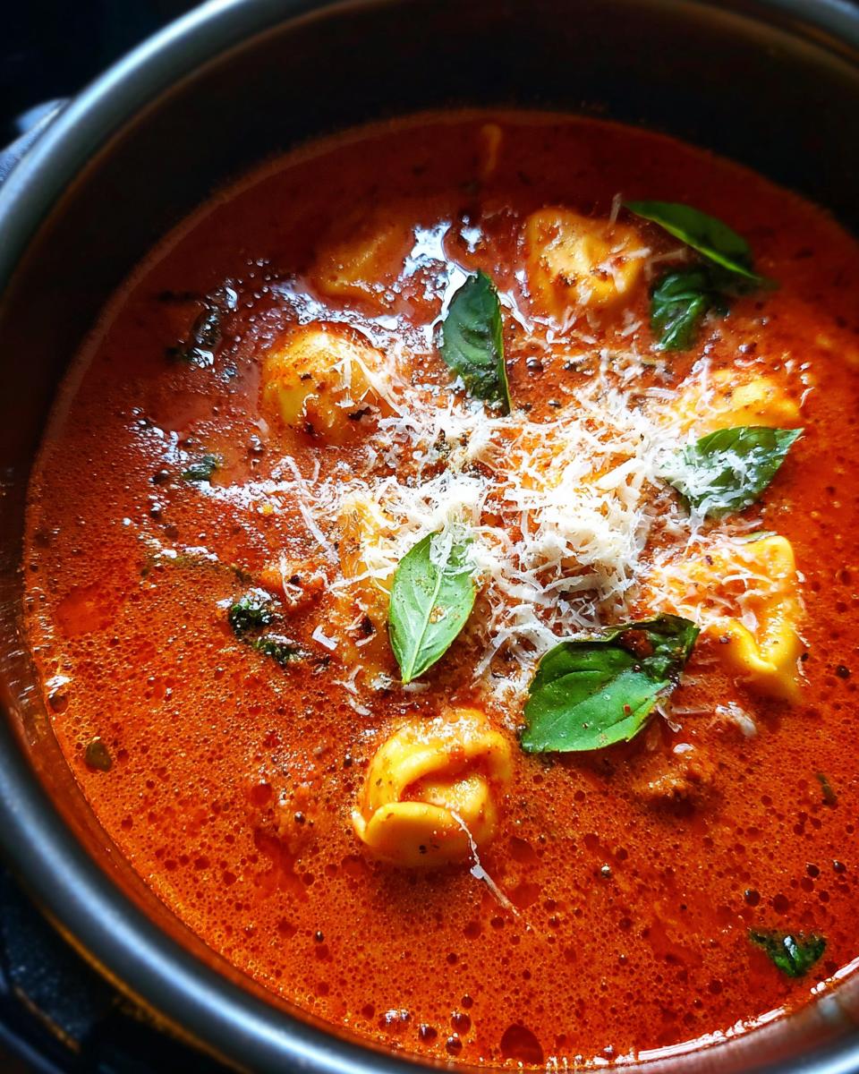 Close-up of Creamy Tomato Tortellini Soup with basil and parmesan.