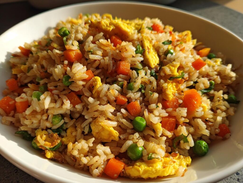 Close-up of Easy Veggie Fried Rice with Egg in a white bowl, with carrots, peas, and egg.