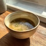 A bowl of delicious Garlic Miso Ramen-Inspired Broth with sesame seeds and green onions.