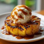 Grilled Pineapple Caramel Sundae topped with vanilla ice cream and caramel sauce, a delicious dessert.