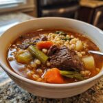 Close-up of a bowl of Hearty Beef & Barley Soup with beef, barley, and vegetables.