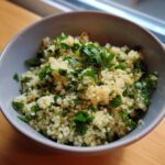 Close-up of a bowl of fresh Herbed Couscous, garnished with chopped herbs.