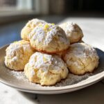 A pile of soft Italian Ricotta Cookies dusted with powdered sugar and lemon zest.
