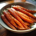 Close-up of tender Maple-Glazed Carrots with Brown Sugar Butter, glistening in a rustic bowl.