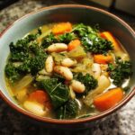 Close-up of a bowl of One-Pot White Bean & Kale Soup with white beans, kale, and carrots.