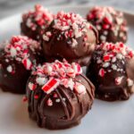 Close-up of Peppermint Bark Stuffed Oreo Balls, covered in chocolate and peppermint.