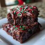 Close-up of two stacked Peppermint Hot Cocoa Brownies with chocolate drizzle and sprinkles.
