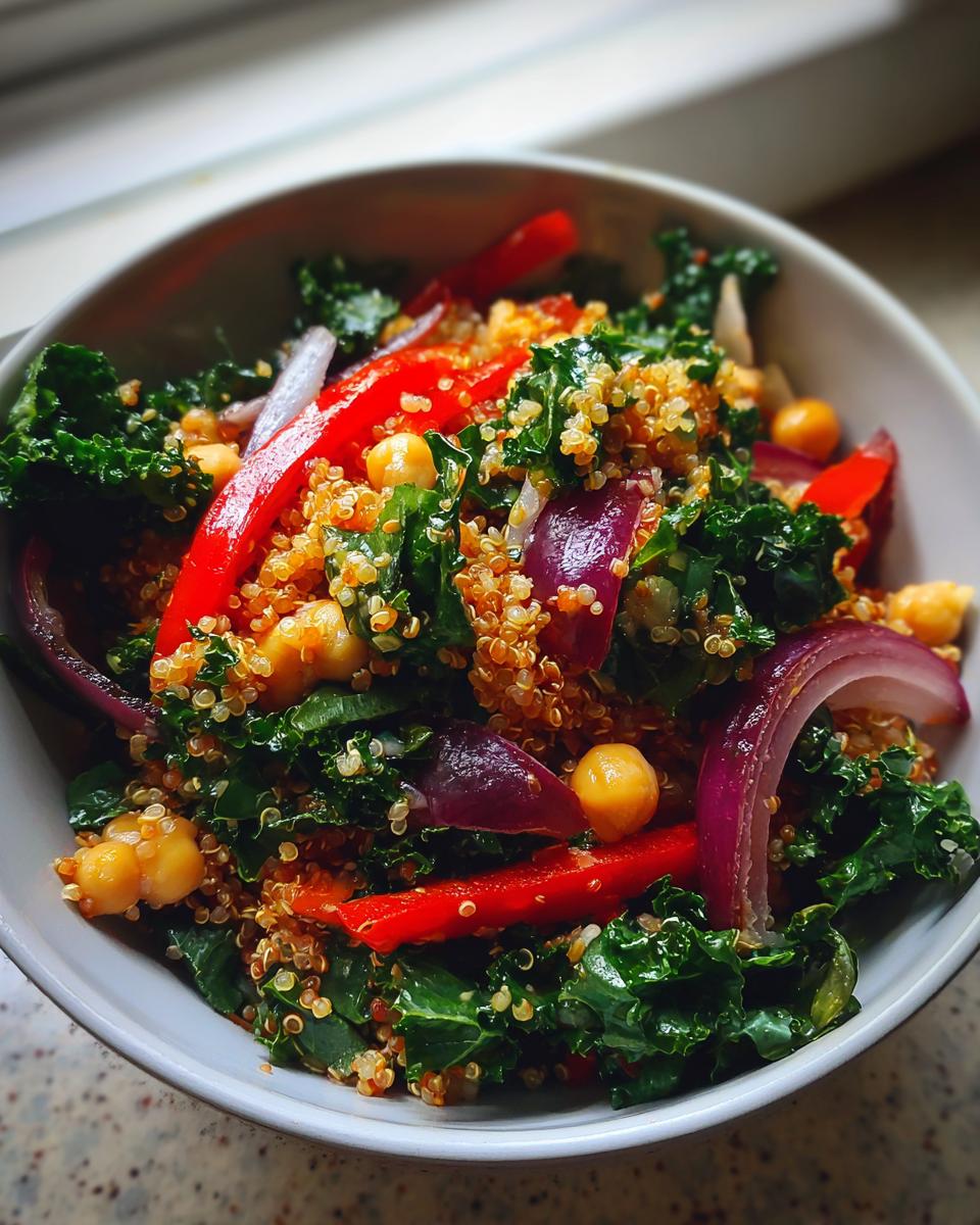 Close-up of a Quinoa Kale Power Bowl with red bell peppers, red onion, and chickpeas.