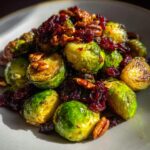 Close-up of roasted Brussels sprouts with dried cranberries and pecans on a plate.