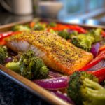 Close-up of Sheet Pan Turmeric Salmon and Veggies, including broccoli, red onion, and bell peppers.