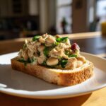 Open-faced sandwich of Simple Tuna and White Bean Salad on toasted bread, served on a white plate.