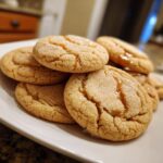 Close-up of a stack of soft-baked Maple Brown Sugar Cookies on a white plate, glistening with sugar.