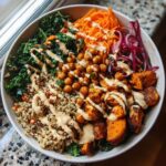 Overhead shot of a Spiced Chickpea and Sweet Potato Buddha Bowl with quinoa, kale, and dressing.