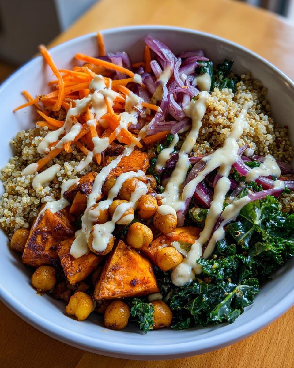 Close-up of a Spiced Chickpea and Sweet Potato Buddha Bowl with quinoa, vegetables, and sauce.