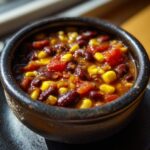 Close-up of a bowl of Spicy Black Bean & Corn Soup, with corn, beans, and tomatoes.