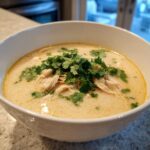 Bowl of delicious Thai-Inspired Coconut Chicken Soup, garnished with fresh cilantro.