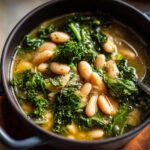 Close-up of a bowl of Tuscan White Bean & Kale Soup, showing beans, kale, and broth.