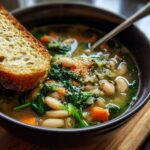 Close-up of a bowl of Tuscan White Bean & Spinach Soup with a slice of toasted bread.