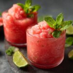 Two glasses of Watermelon Margarita Sorbet Floats garnished with mint and lime.