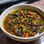 Close-up of a bowl of Wild Rice & Mushroom Soup, featuring mushrooms, wild rice, and herbs.