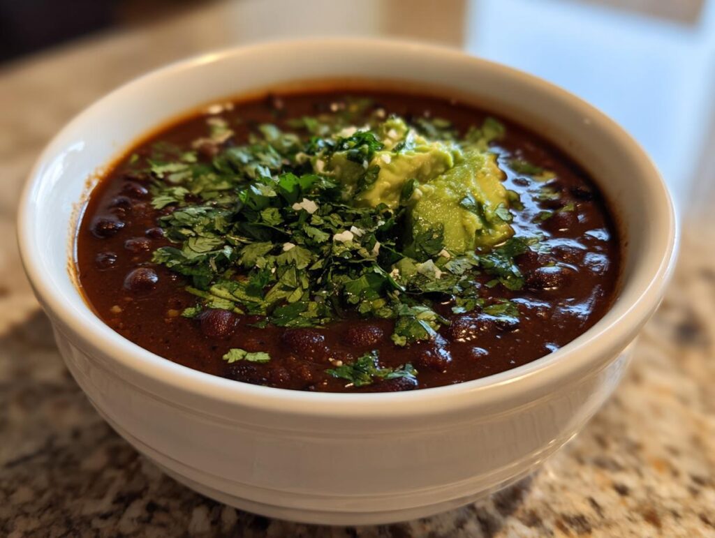 A bowl of delicious Zesty Black Bean Soup, topped with fresh cilantro and avocado.