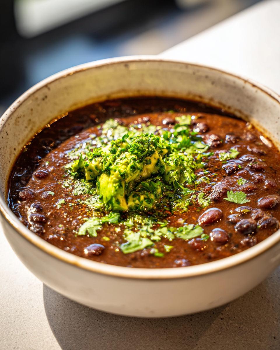 Close-up of a bowl of Zesty Black Bean Soup, topped with avocado and cilantro.