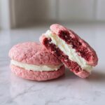 Close-up of two Pink Velvet Cookie sandwiches filled with white cream, showcasing the Pink Velvet Cookie Recipe.