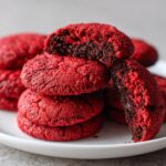 Close-up of a stack of delicious Red Velvet Cookies on a white plate, showing their soft texture.