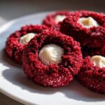 Close-up of delicious Red Velvet Thumbprint Cookies with cream cheese filling on a white plate.