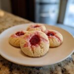 A plate of four freshly baked Strawberry Kiss Cookies, a perfect treat.